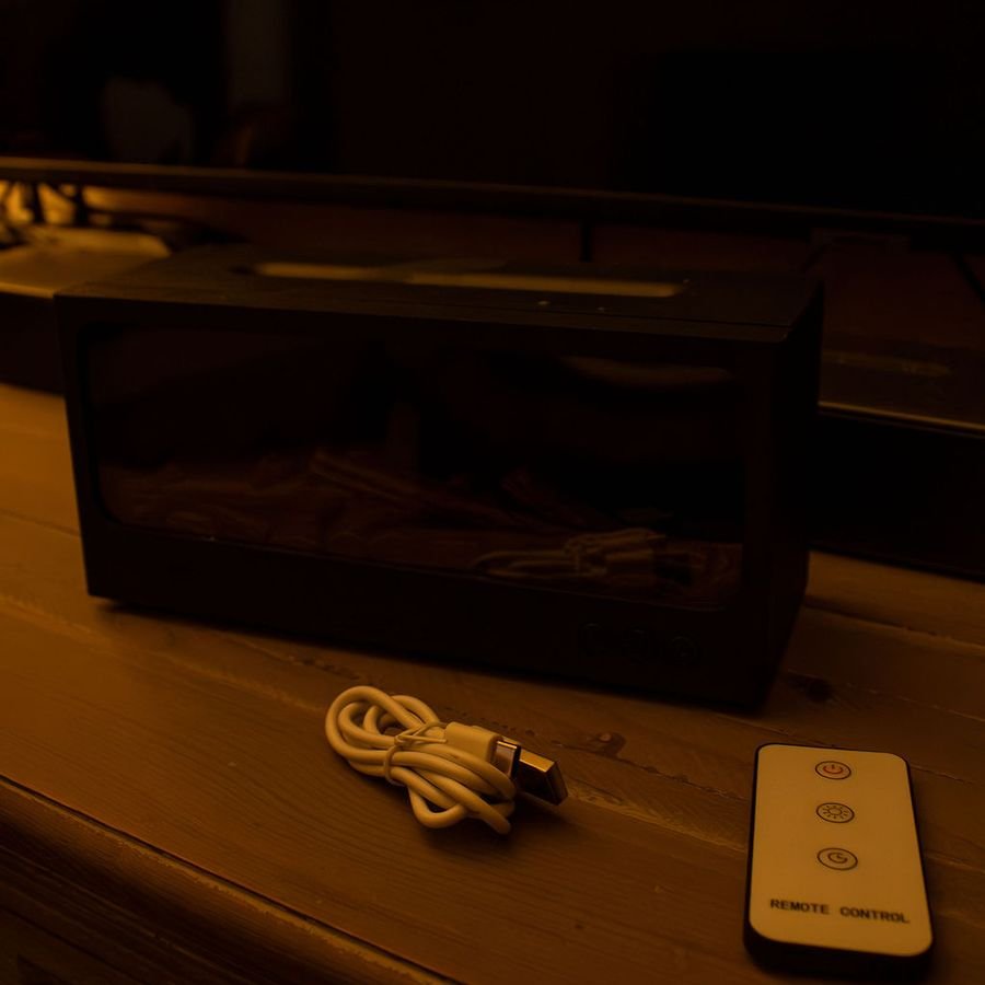 De zwarte Solafera Haard uit, met de afstandsbediening en de USB-C kabel ervoor